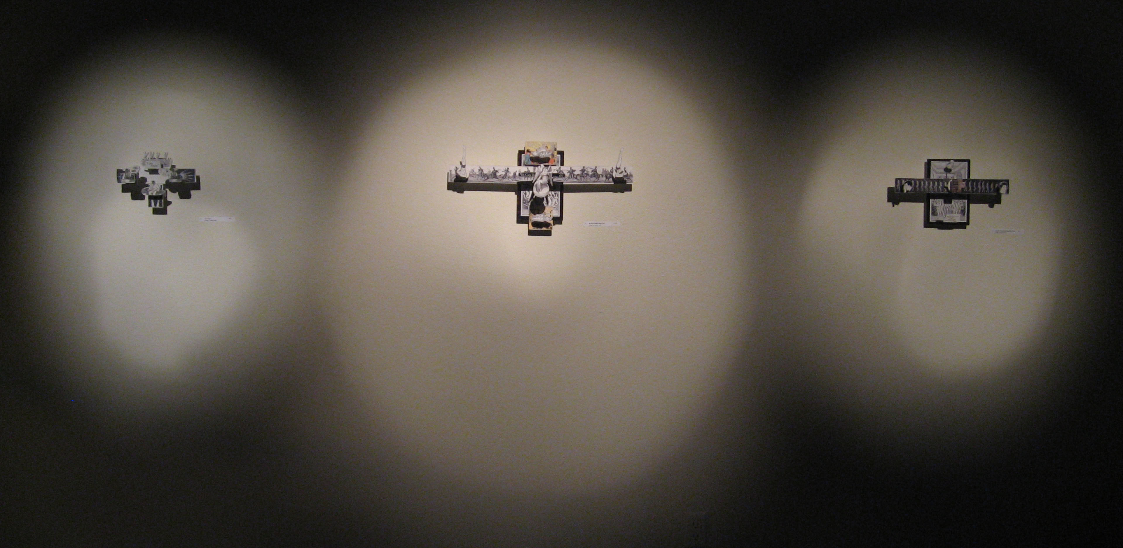 Three abstract sculptures displayed on a dark wall, each illuminated by individual spotlights.